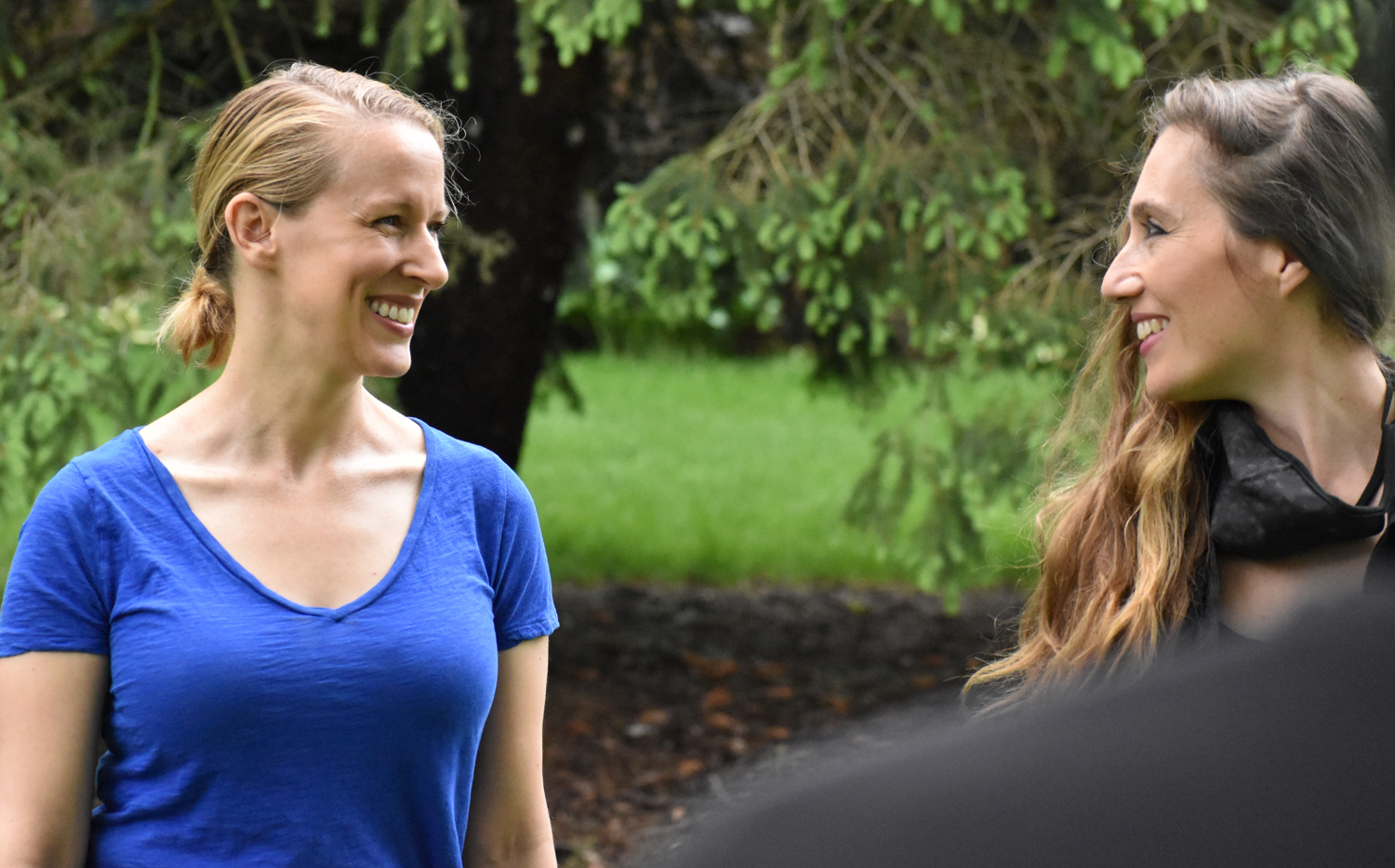 Two women actors smile while doing an activity outdoors